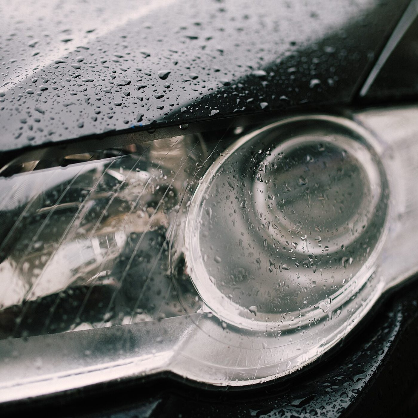 Close-up of a car headlight covered in raindrops