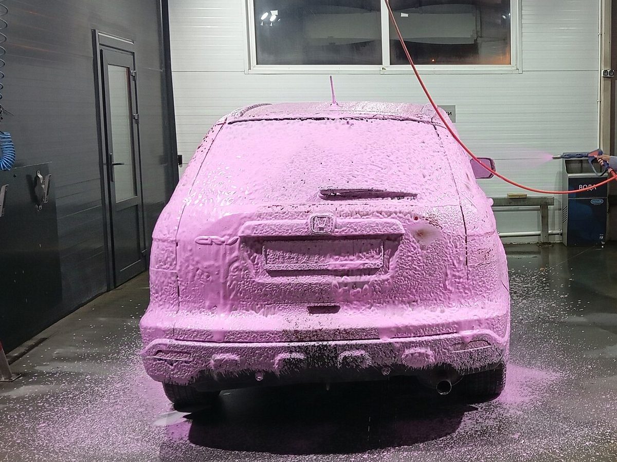 SUV covered in pink foam in a wash bay